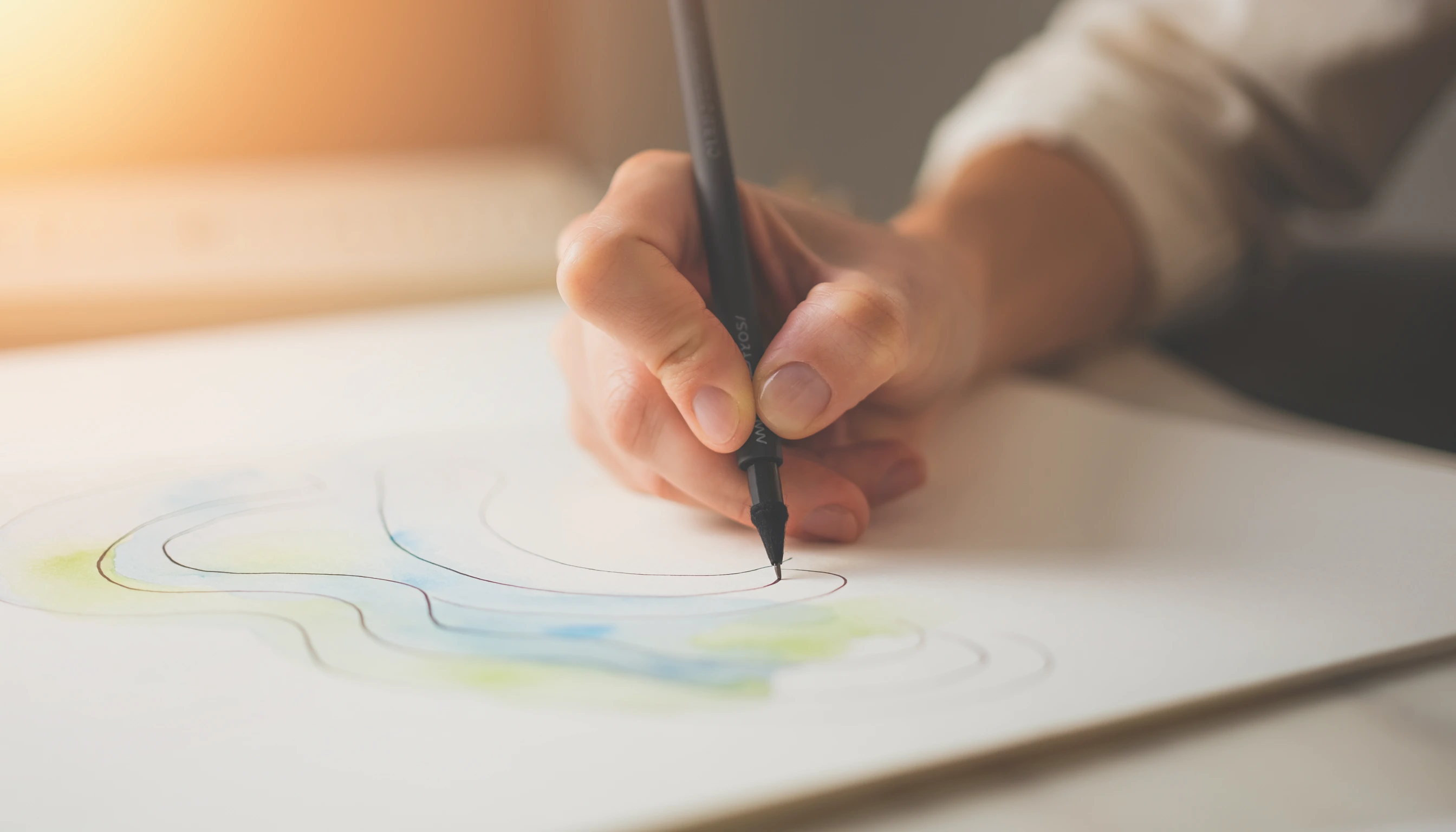 Main tenant un stylo et traçant des lignes courbes sur une feuille blanche pour l'exercice de dessin respiratoire